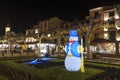 Snowman illuminated on a street with Christmas stalls