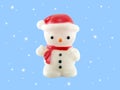 close up single snowman lamp wearing red hat and scarf with falling snow isolated on blue background