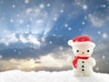 white snowman lamp wearing red hat and scarf on snow hill with falling snow on dramatic sky sunset background Royalty Free Stock Photo