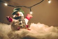 Snowman and light bulb stand among pile of snow at silent night, light up the hopefulness and happiness in Merry christmas and hap Royalty Free Stock Photo