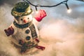 Snowman and light bulb stand among pile of snow at silent night, Merry christmas and Happy new year night. Royalty Free Stock Photo