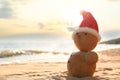 Snowman made of sand with Santa hat on beach, space for text. Christmas vacation