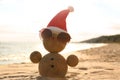 Snowman made of sand with Santa hat and sunglasses on beach. Christmas vacation Royalty Free Stock Photo