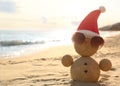 Snowman made of sand with Santa hat and sunglasses on beach, space for text. Christmas vacation Royalty Free Stock Photo