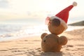 Snowman made of sand with Santa hat and sunglasses on beach near sea, space for text. Royalty Free Stock Photo
