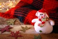 Snowman next to cozy knitted blanket on wooden table