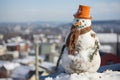 snowman with a pipe and carrot nose on a snowy rooftop