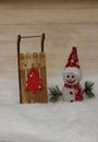 Snowman in a red cap with wooden sleigh Royalty Free Stock Photo