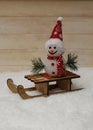Snowman in a red cap with wooden sleigh Royalty Free Stock Photo