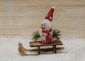 Snowman in a red cap with wooden sleigh Royalty Free Stock Photo