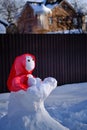 Snowman in a red shawl in the shape of a figure with a baby. Suburban Winter landscape. Selective focus