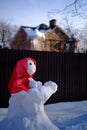 Snowman in a red shawl in the shape of a figure with a baby. Suburban Winter landscape. Selective focus