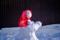 Snowman in a red shawl in the shape of a figure with a baby. Suburban Winter landscape. Selective focus