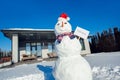 Winter time. Snowman with for sale board and keys on a yard near house no people