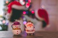 Snowman and Santa baubles with Christmas lights and children in the background