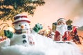 Snowman and Santa claus hold bell among pile of snow at silent night with a light bulb, light up the hopefulness and happiness