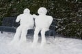 Snowman and snowwoman on a park bench in Winter