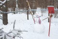 The snowman stands in the snow with a broom and a shovel. Royalty Free Stock Photo