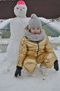 Little girl child in winter sculpts a snowman from the snow.