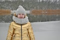 Little girl child in winter sculpts a snowman from the snow.