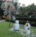 Snowman and three penguins on a green lawn, garden sculpture, palm trees and decorative trees