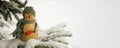 Snowman, toy on the background of a snowy Christmas tree. Snowing. Selective focus, blurred winter background. The