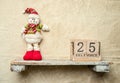 snowman toy on a shelf, wooden calendar with 25 december date, christmas banner, copy space for promo or ad