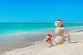 Snowmans family at sea beach in santa hat.