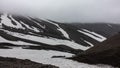 Snowmelt lies on the rocky mountain slopes.