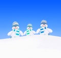 Snowmen family in knitted scarfs at winter snow against sky