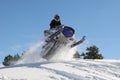 Snowmobile jumping on powdery hill