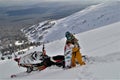 Snowmobile and snowboard rider with snowboard on the mountain top.