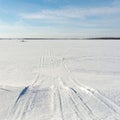 Snowmobile tracks on a winter field. Sunny winter day with blue sky Royalty Free Stock Photo