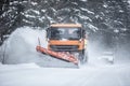 Snowplow clearing road from snow in the forest with traffic lining up behind the truck Royalty Free Stock Photo