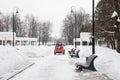 A snowplow removes snow on the road in the park.