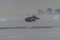 Snowplow removing snow from runways and roads in airport during snow storm, view through window