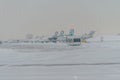 Snowplow removing snow from runways and roads in airport during snow storm, view through window