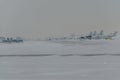 Snowplow removing snow from runways and roads in airport during snow storm, view through window