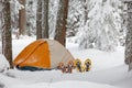 Snowshoes left in front of orange tent in winter forest