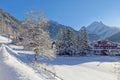 Snowy alpine village in Italy illuminated by sun with mountains in the background Royalty Free Stock Photo