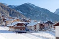 Snowy alpine village in Italy illuminated by sun with mountains in the background Royalty Free Stock Photo