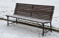 Snowy benches near the supporting concrete gray wall in the park. Paving and metal low fences protect ornamental flower beds from