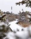 Snowy boardwalk path leading to a lighthouse in a wintery scene. Fire Island Long Island Royalty Free Stock Photo