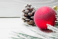 Snowy branch christmas tree and cone and red ball on white wooden vintage background Royalty Free Stock Photo