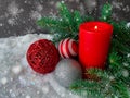 Snowy Christmas holiday mood. Red candle with decoration baubles with spruce tree on snow Royalty Free Stock Photo