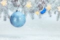 Snowy christmas tree branches decorated with blue glass ball, drum toy and garland lights Royalty Free Stock Photo