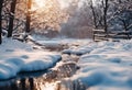 snowy, cold landscape with wooden benches and stream in front of trees