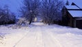Snowy country road at evening time. Street lamp illuminating snow trail at winter night. Beautiful nature landscape with Royalty Free Stock Photo