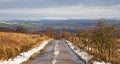 A snowy country road looking towards high, snow covered moors in the background