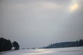 Countryside in winter by grey sky and glaring sunlight